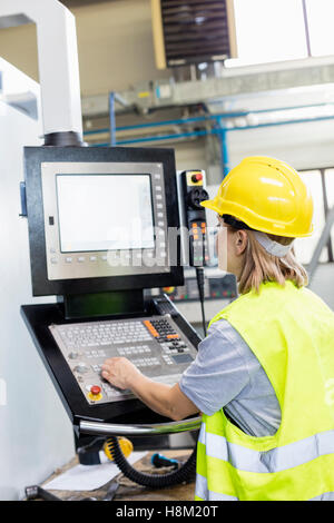 Travailleuse de l'utilisation de machines sur le panneau en usine Banque D'Images