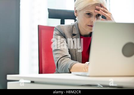 La maturité se raidit businesswoman using laptop at desk in office Banque D'Images