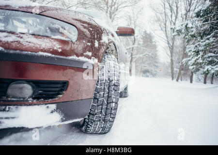 Voiture sur route forestière couverte de neige. À partir de la vue du sol, selective focus sur les pneus hiver Banque D'Images