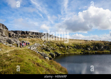 Les randonneurs randonnée par un petit lac de montagne en Rhinog montagnes du sud du Parc National de Snowdonia. Trawsfynydd, Gwynedd, Pays de Galles, Royaume-Uni Banque D'Images