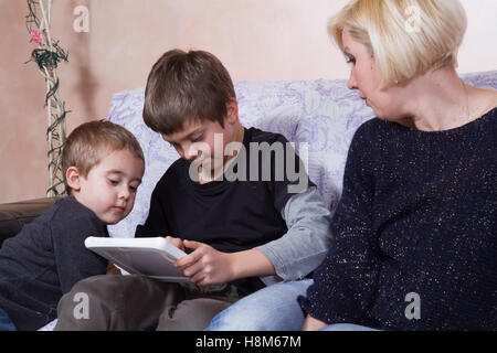 Frères jouant avec une tablette près de leur mère Banque D'Images