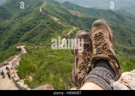 Mutianyu, Chine - vue rapprochée d'un touristiques's chaussures avec la Grande Muraille de Chine en arrière-plan. Le mur s'étend sur plus de 6, Banque D'Images