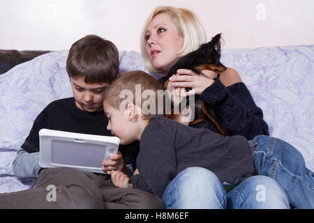 Frères jouant avec une tablette près de leur mère Banque D'Images