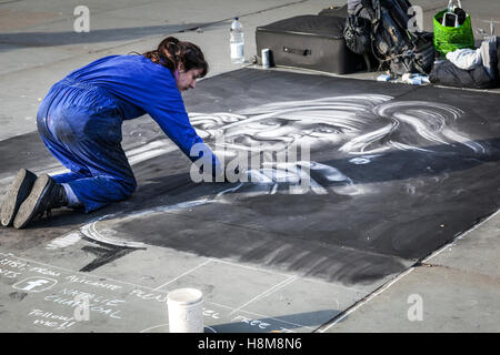 Une femme artiste habillé en salopette bleue dresse le portrait au fusain sur la chaussée à l'extérieur de la Galerie Nationale Banque D'Images