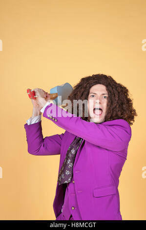 Caucasian man with afro portant costume violet avec la guitare derrière sa tête Banque D'Images