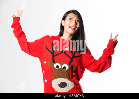 Portrait de femme en pull de Noël article faisant la paix signer sur fond gris Banque D'Images