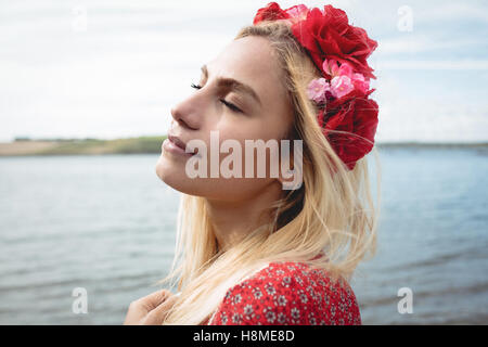 Femme blonde portant un diadème de fleurs debout près d'une rivière Banque D'Images