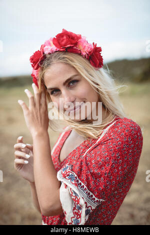 Femme blonde portant un diadème de fleurs standing in field Banque D'Images