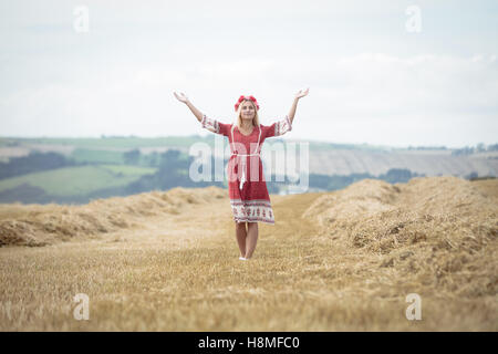 Blonde woman standing in field with her arms propagation Banque D'Images