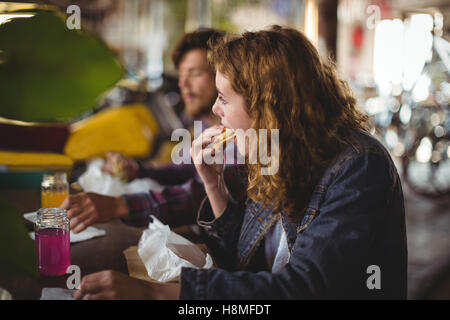 Couple assis à table et eating sandwich Banque D'Images