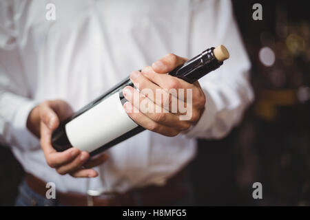 Section intermédiaire de bar offres tenant une bouteille de vin Banque D'Images