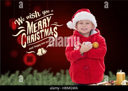 Happy boy in santa hat holding christmas baubles Banque D'Images