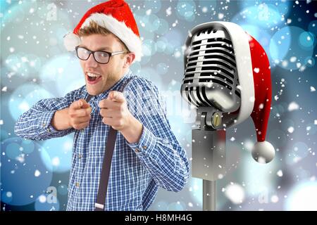 Microphone vers Man gesturing with santa hat contre l'arrière-plan création numérique Banque D'Images