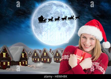 Beautiful woman in santa hat holding christmas gift Banque D'Images
