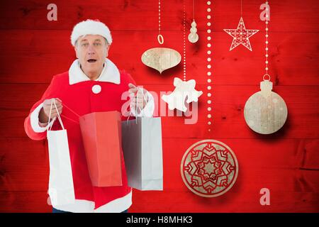 L'homme en costume santa holding shopping bags contre l'arrière-plan création numérique Banque D'Images