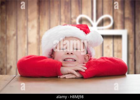 Portrait of happy boy in santa hat leaning on table Banque D'Images