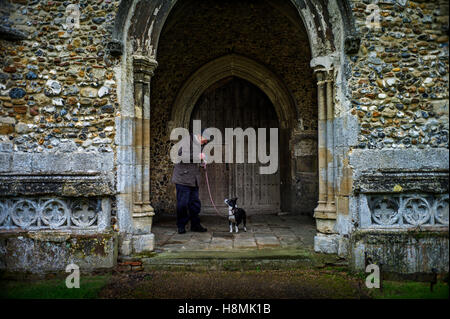 Thaxted Essex England, UK. L'homme et son chien à Thaxted Église. Mars 2016 L'église paroissiale de St John, construit entre 1340 et 1510, est renommée pour son battant renforcé spire, qui est de 181 pieds de haut et est la seule pierre médiévale spire dans le comté. Windows perpendiculaires et un vitrail représentant Adam et Eve. L'église, qui se dresse sur une colline et domine la ville, est souvent appelée "la cathédrale d'Essex". De 1910 à 1942, le vicaire a été Conrad Noel, connu sous le nom de "Vicaire Rouge" en raison de son bien connu le socialisme chrétien. Banque D'Images