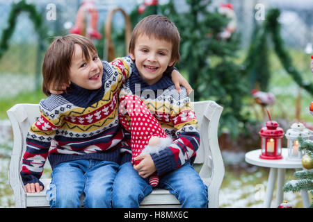 Deux adorables enfants, garçon frères, s'amusant à l'extérieur dans le jardin à Noël autour de l'arbre de Noël décoré tout en sn Banque D'Images