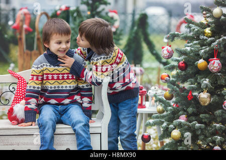 Deux adorables enfants, garçon frères, s'amusant à l'extérieur dans le jardin à Noël autour de l'arbre de Noël décoré tout en sn Banque D'Images