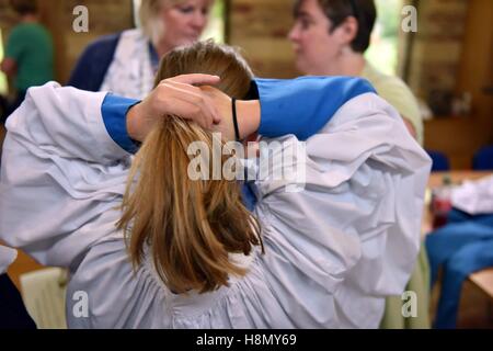 Choriste fille en soutane et surplis obtenant les poils. Les Choristes à soutane montage et répétition pour la messe. Banque D'Images