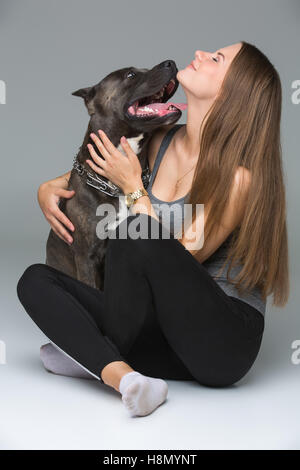 Belle fille avec Stafford Terrier gris Banque D'Images