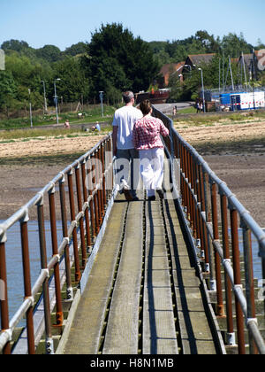 Couple d'âge moyen à marcher le long de la jetée en bois au Club de voile de Southampton, Southampton, Hampshire Rockfield, UK Banque D'Images