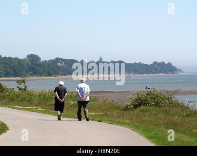 Personnes âgées en train de marcher le long de la Parade, Weston Weston Shore Rockfield, Southampton, Hampshire, Royaume-Uni avec Royal Victoria Country Park Banque D'Images