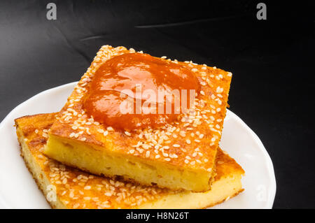 Tranche de gâteau au fromage avec des graines de sésame et confiture d'abricot sur un fond noir Banque D'Images