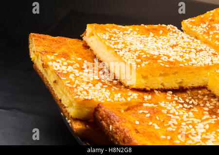 Tranche de gâteau au fromage avec graines de sésame sur un fond noir Banque D'Images