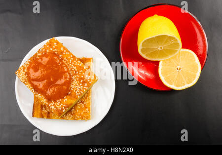 Tranche de gâteau au fromage avec des graines de sésame, confiture d'abricot et de tranches de citron sur un fond noir Banque D'Images