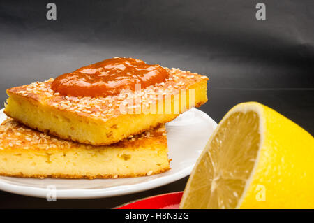 Tranche de gâteau au fromage avec des graines de sésame, confiture d'abricot et de tranches de citron sur un fond noir Banque D'Images