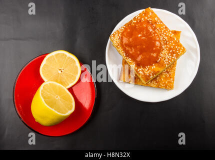 Tranche de gâteau au fromage avec des graines de sésame, confiture d'abricot et de tranches de citron sur un fond noir Banque D'Images