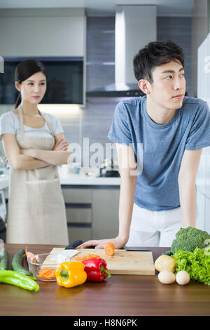 Jeune couple chinois ignorant les uns les autres dans la cuisine Banque D'Images