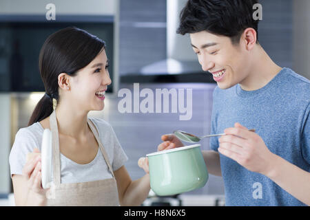 Les jeunes Chinois heureux couple cooking in kitchen Banque D'Images