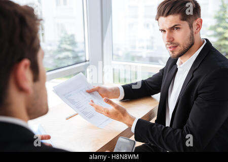 Young businessman sitting et de donner des documents à son collègue de bureau Banque D'Images