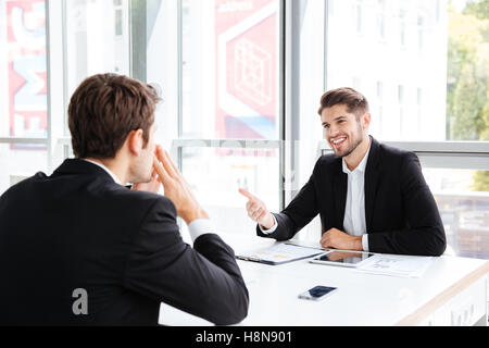 Deux jeunes hommes d'heureux assis et parlant le meeting in office Banque D'Images