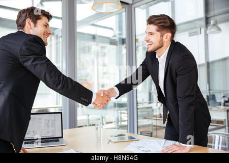 Joyeux deux jeunes businessmen shaking hands on business meeting Banque D'Images