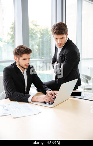 Deux jeunes hommes d'concetrated using laptop in office Banque D'Images