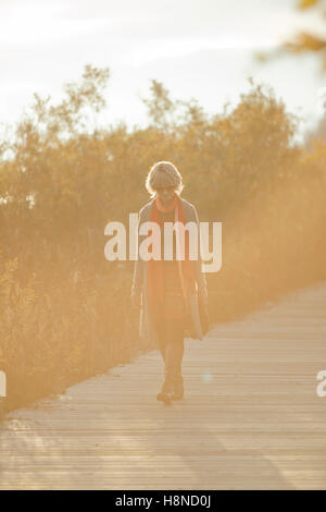 Woman walking along boardwalk at sunset Banque D'Images