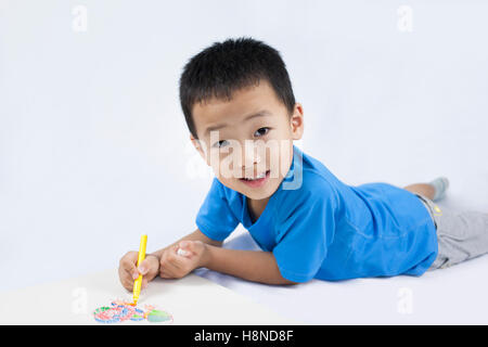 Happy little Chinese boy coloring couchée sur le plancher Banque D'Images