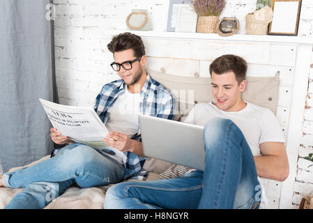 Heureux couple gay lire ensemble dans la chambre Banque D'Images