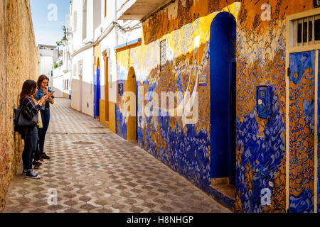 Les touristes de prendre des photos d'une fresque de rue peint par un artiste local, Asilah, Maroc Banque D'Images