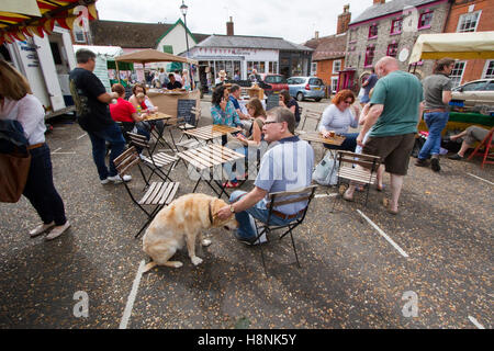 Les gens assis à un café extérieur/cafe dans un marché de la ville de Suffolk. Banque D'Images