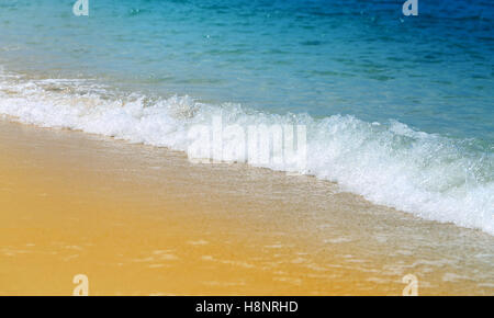 De belles vagues sur le sable de la mer jaune photographiée en close-up Banque D'Images