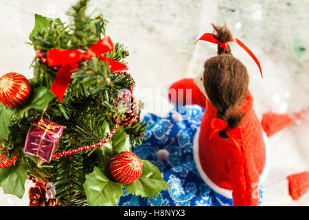 Poupée en tissu souple près d'un arbre de Noël avec des cadeaux. Banque D'Images