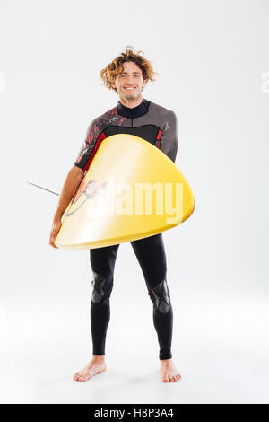 Portrait d'un jeune surfeur smiling holding surf board isolé sur fond blanc Banque D'Images