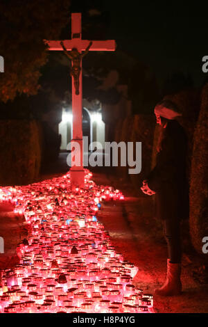 Une vue de la nuit d'une femme en prière devant la croix de cimetière à Zagreb, Croatie. Banque D'Images