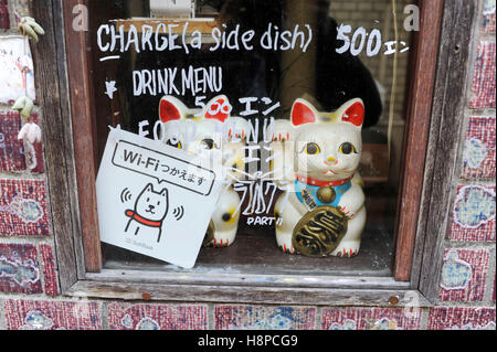 Le Japon, Tokyo : maneki-neko (littéralement 'cat' signe) dans une fenêtre Afficher Banque D'Images