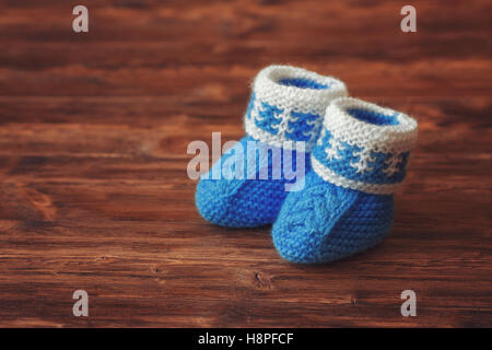 Chaussons pour bébé au crochet bleu sur fond de bois, copyspace, tons vintage Banque D'Images