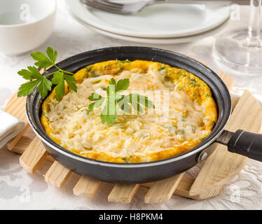 Frittata à la ricotta italienne, cheddar, gruyère et parmesan dans une poêle sur une table. Banque D'Images